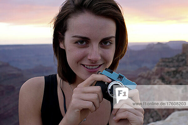 Eine junge Frau fotografiert den Grand Canyon bei Sonnenuntergang.