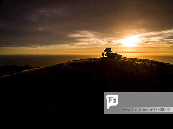 Silhouette of campers in Big Sur using a rooftop tent.