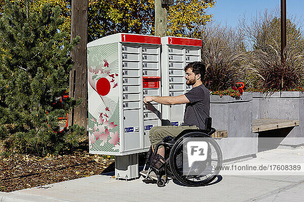 Young paraplegic man at the community mailboxes getting his mail; Edmonton  Alberta  Canada