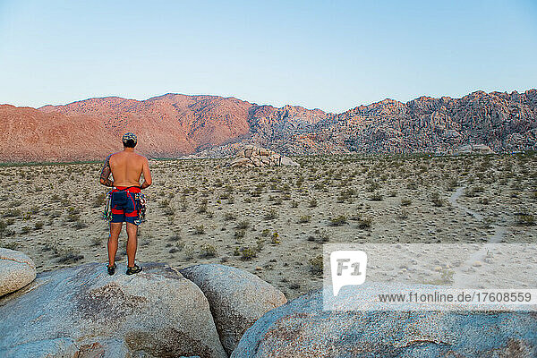 A climber watches the sunset from atop a granite block in Joshua Tree National Park.