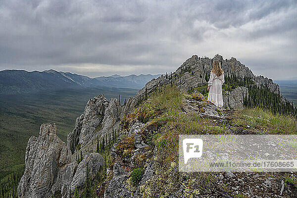 Woman in a white dress standing in the beautiful Yukon landscapes; Yukon  Canada