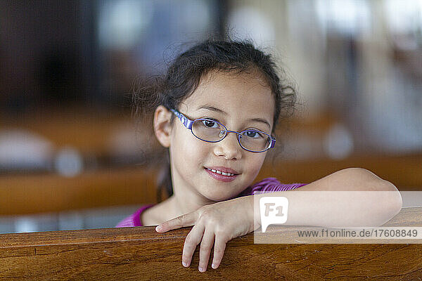 Porträt eines jungen Mädchens mit Brille  das sich auf der Star Ferry an ein Holzgeländer lehnt; Hongkong  China