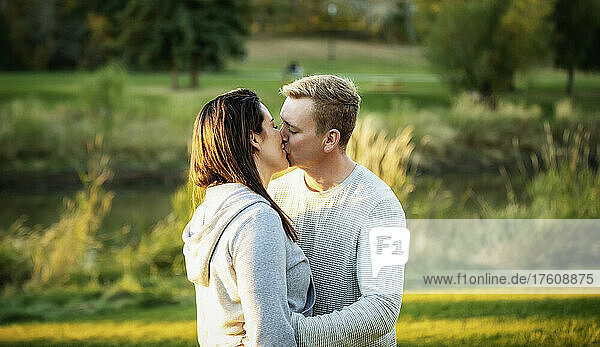 A mid adult couple sharing a kiss in a park at sunset; St. Albert  Alberta  Canada