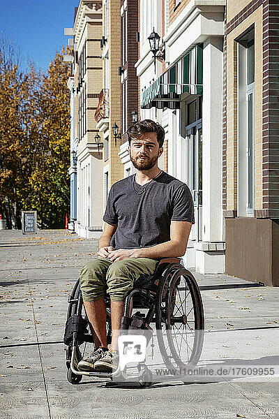Outdoor portrait of a young paraplegic man in his wheelchair on a city walkway on a beautiful fall day; Edmonton  Alberta  Canada