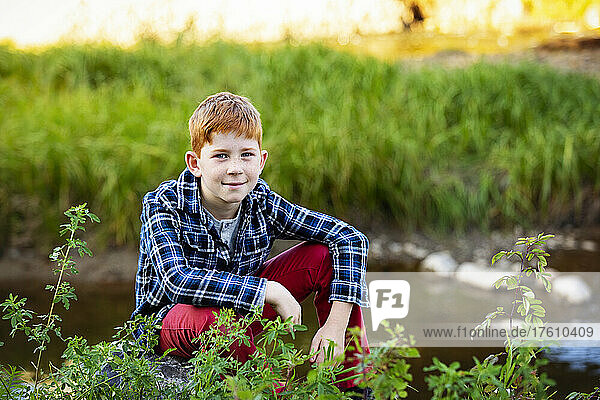 Outdoor portrait of a boy with red hair sitting beside a creek; Edmonton  Alberta  Canada