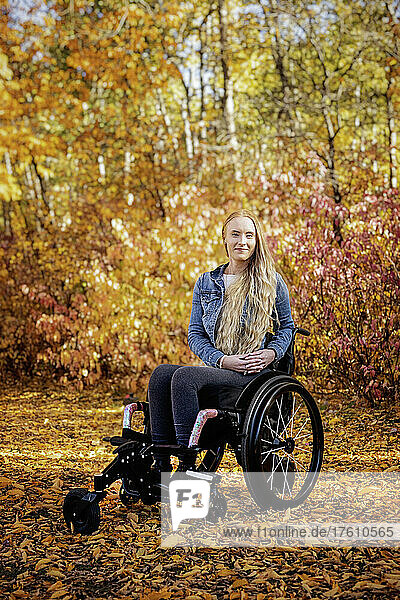 Eine junge querschnittsgelähmte Frau in ihrem Rollstuhl in einem Park an einem schönen Herbsttag; Edmonton  Alberta  Kanada