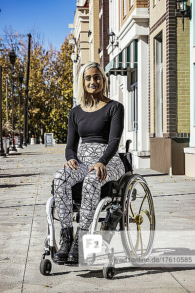 Außenporträt einer jungen querschnittsgelähmten Frau in ihrem Rollstuhl auf einem städtischen Gehweg an einem schönen Herbsttag; Edmonton  Alberta  Kanada