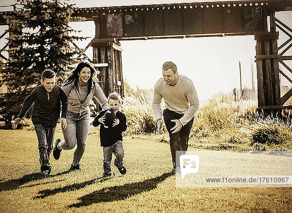 Young family in a game of football on a beautiful autumn day in a city park; St. Alberta  Alberta  Canada