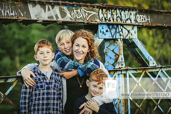 Porträt einer Mutter mit drei Jungen auf einer Brücke in einem Park im Herbst; Edmonton  Alberta  Kanada