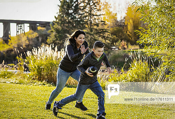 Mutter  die ihren Sohn an einem schönen Herbsttag in einem Stadtpark mit einem Fußballspiel verfolgt; St. Alberta  Alberta  Kanada