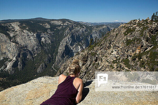 At the Taft Point hiking trail peak  a hiker looks over the edge to Yosemite Valley below.; Yosemite National Park  California