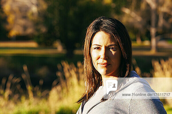Outdoor portrait of a mid adult woman with brunette hair  illuminated by the sunlight in autumn; St. Albert  Alberta  Canada