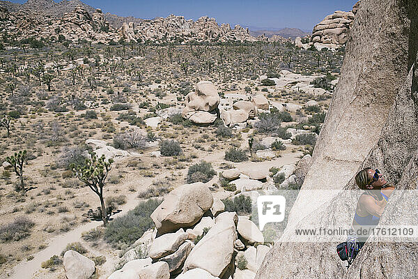 A young woman climbs Double Cross in Joshua Tree National Park.