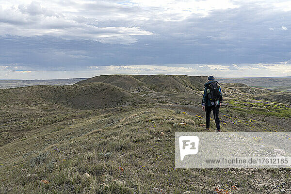 Woman walking on a butte towards 70 Mile butte in Grasslands National Park; Val Marie  Saskatchewan  Canada