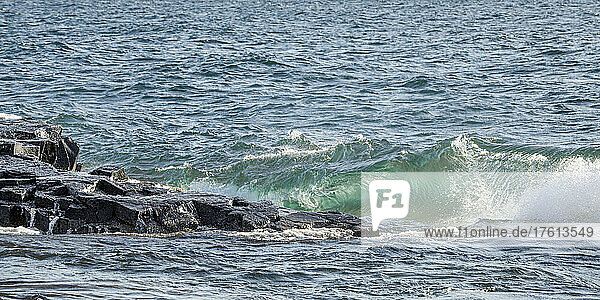 Wellen aus klarem  grünem Wasser plätschern gegen ein felsiges Ufer des Lake Superior; Grand Portage  Minnesota  Vereinigte Staaten von Amerika