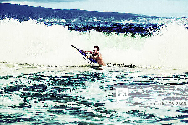 Ein Mann  der bereit ist  auf einem Bodyboard eine Welle zu reiten  am D. T. Fleming Beach mit der Insel Molokai im Hintergrund; Kapalua  Maui  Hawaii  Vereinigte Staaten von Amerika