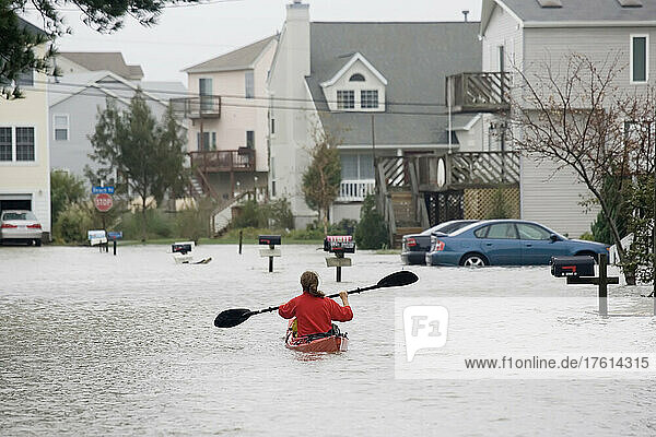 Eine Frau paddelt in einem Seekajak mitten auf einer überfluteten Straße; Hampton  Virginia.