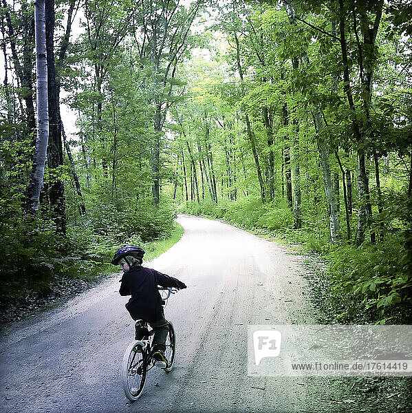 Ein achtjähriger Junge fährt mit seinem Fahrrad auf einem Waldweg in der Nähe des Sebago Lake  Maine; Sebago Lake  Maine  Vereinigte Staaten.