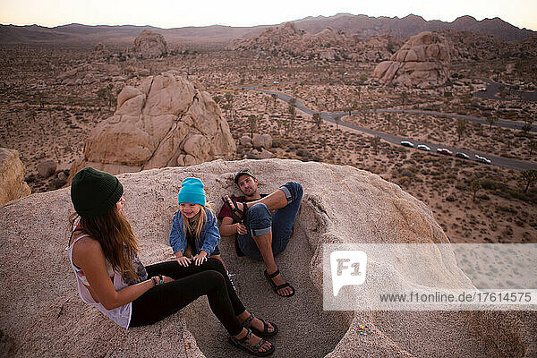 Hikers and a child on top of Cyclops Rock in Joshua Tree National Park at sunset.