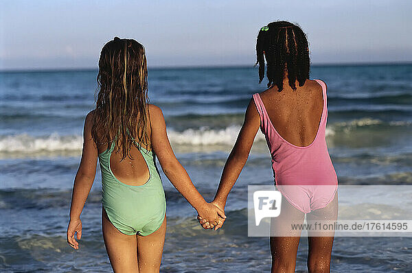 Back View of Two Girls in Swimwear  Holding Hands on Beach South Andros  The Bahamas