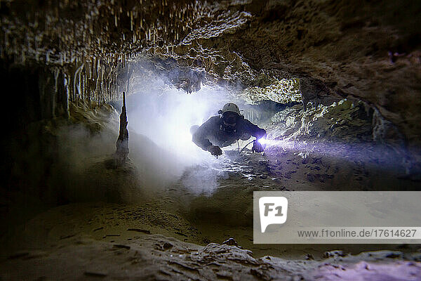 Ein Höhlentaucher geht durch einen verschlammten Gang.