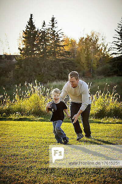 Father playing football with his young son in a park in autumn; St. Albert  Alberta  Canada