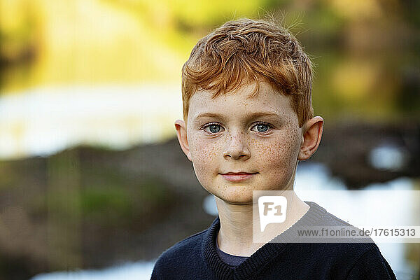 Outdoor portrait of boy with red hair and freckles and blurred autumn colours in the background; Edmonton  Alberta  Canada