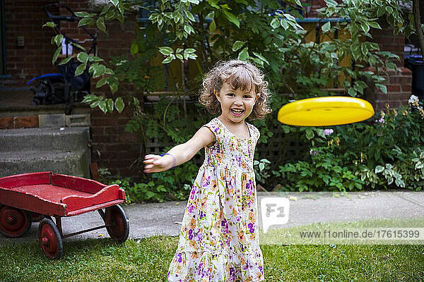 Vorschulkind wirft Frisbee in die Kamera in ihrem Garten zu Hause; Toronto  Ontario  Kanada