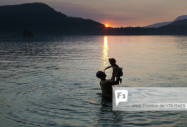 Father and young daughter play in a lake at sunset  Ruby Lake on the Sunshine Coast of BC  Canada; British Columbia  Canada