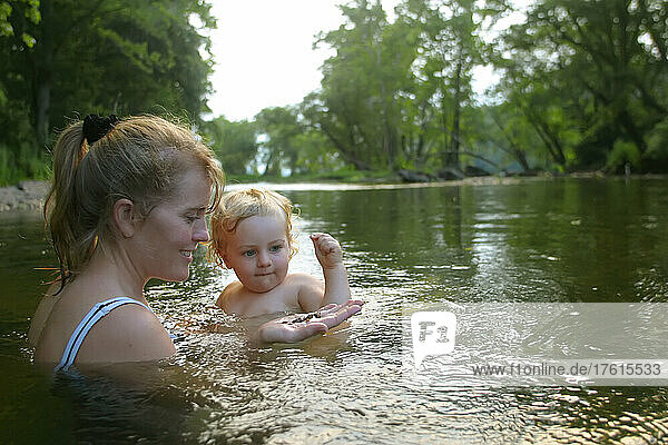 Mutter und Baby schwimmen und spielen mit Steinen im Potomac River; Potomac River  Maryland.