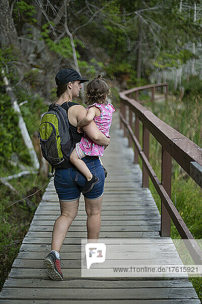 Eine Mutter trägt ihre kleine Tochter auf einem Wanderweg im Smuggler Cove Marine Provincial Park an der Sunshine Coast von BC  Kanada; British Columbia  Kanada