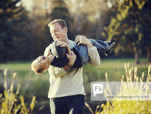 Father playing with his young son in a park in autumn; St. Albert  Alberta  Canada
