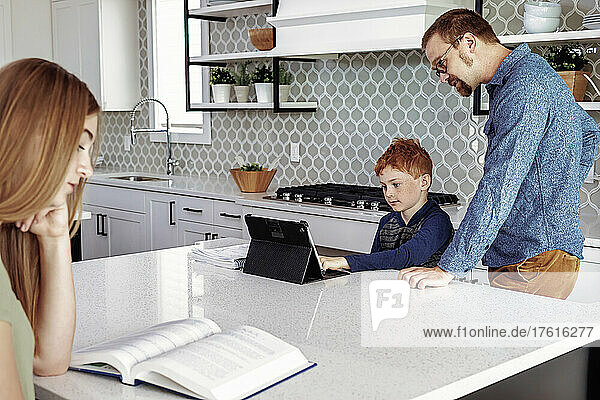 Father helping son with homework in the home kitchen; Edmonton  Alberta  Canada