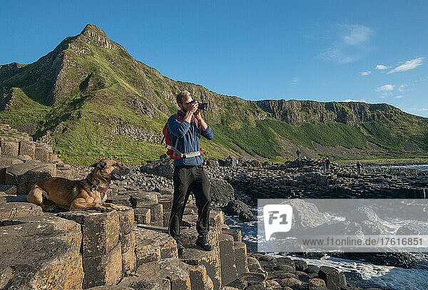 Ein junger Mann und sein Hund erkunden den Giant's Causeway in Nordirland  Vereinigtes Königreich.