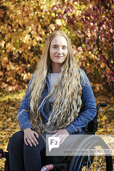A young paraplegic woman in her wheelchair in a park on a beautiful fall day; Edmonton  Alberta  Canada