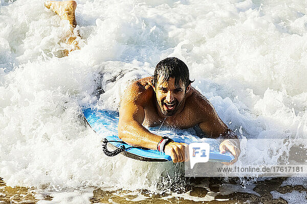 Close-up of a man riding a wave on a bodyboard into the shore at D. T. Fleming Beach; Kapalua  Maui  Hawaii  United States of America
