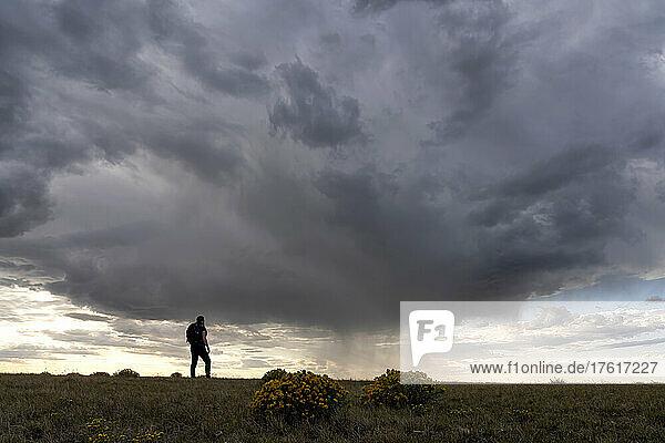 Woman watching a rain shower heading toward her on the Canadian prairies; Val Marie  Saskatchewan  Canada