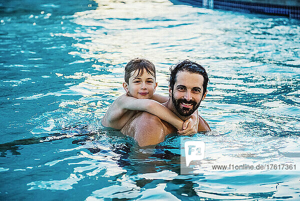 Portrait of a father swimming with his young son in a swimming pool at a resort in Ka'anapali; Ka'anapali  Maui  Hawaii  United States of America