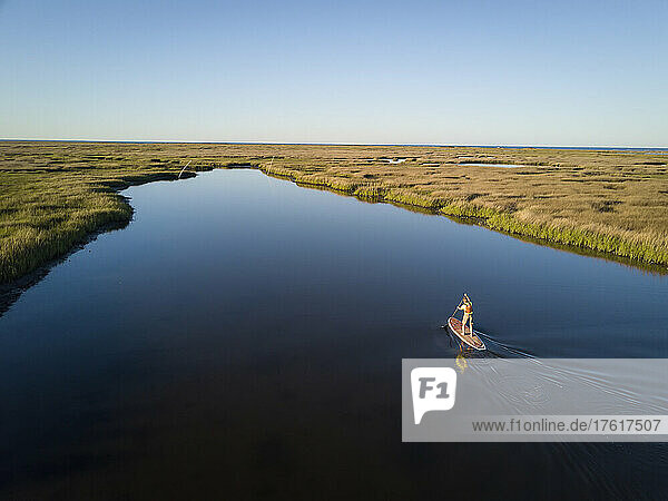 A stand up paddle boarder cruises through the salt marsh of the Plumtree National Wildlife Reserve.; Poquoson  Virginia  Virginia  USA