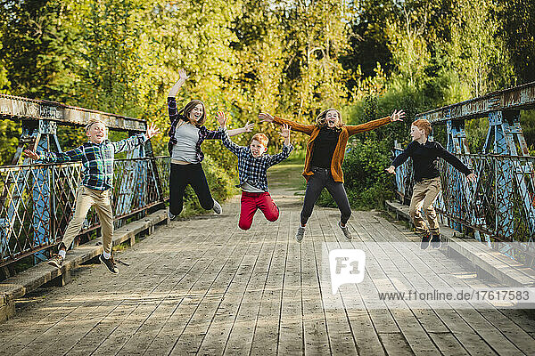 Fünf Geschwister in einer Reihe springen in der Luft auf einer Parkbrücke; Edmonton  Alberta  Kanada
