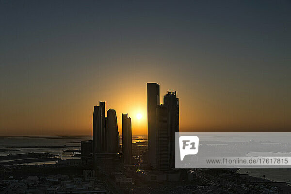 Blick auf die silhouettierten Hochhäuser entlang der Küste des Persischen Golfs bei Sonnenuntergang; Abu Dhabi  Vereinigte Arabische Emirate