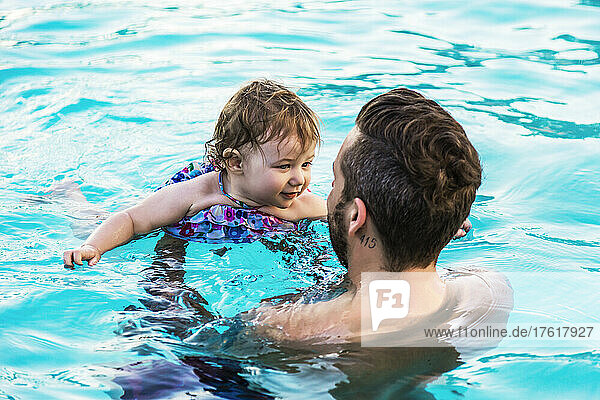 A father swims with his young daughter in the pool at a resort in Ka'anapali; Ka'anapali  Maui  Hawaii  United States of America