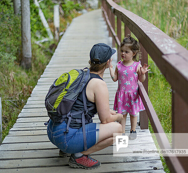 Mother and young daughter hold hands and walk down a trail on a hike together in Smuggler Cove Marine Provincial Park along the Sunshine Coast of BC  Canada; British Columbia  Canada
