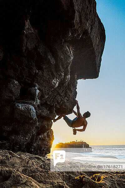 Ein Mann beim Bouldern am Strand von Oahu.