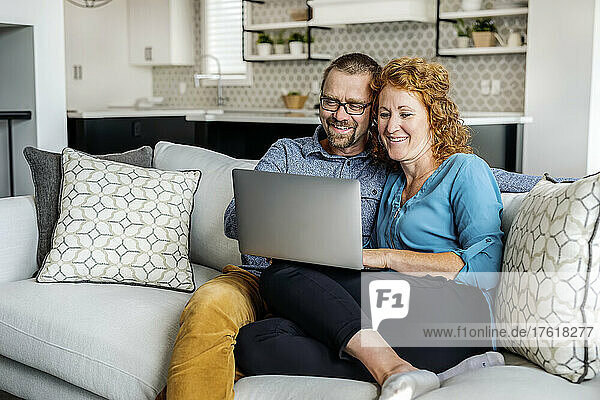 Ehepaar  das zu Hause auf einer Couch sitzt und seinen Laptop benutzt; Edmonton  Alberta  Kanada