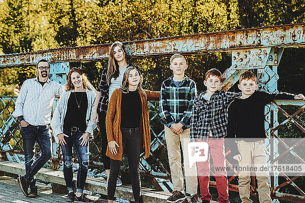 Family of seven standing on a bridge for a family portrait in a city park in autumn; Edmonton  Alberta  Canada