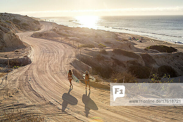 Zwei Frauen suchen bei Sonnenaufgang an der Küste von Cabo nach Wellen.