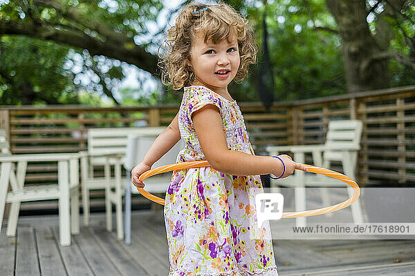 Preschooler girl plays with hula hoop and looks at the camera; Toronto  Ontario  Canada