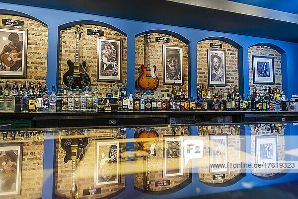 Display of photographs and guitars of Blues musicians along a bar with bottles of alcohol in a Blues Club; Chicago  Illinois  United States of America