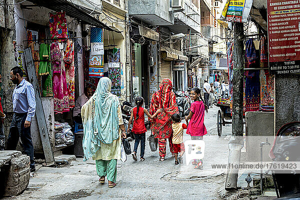 Mutter und Kinder gehen gemeinsam eine traditionelle Straße in Indien entlang; Indien